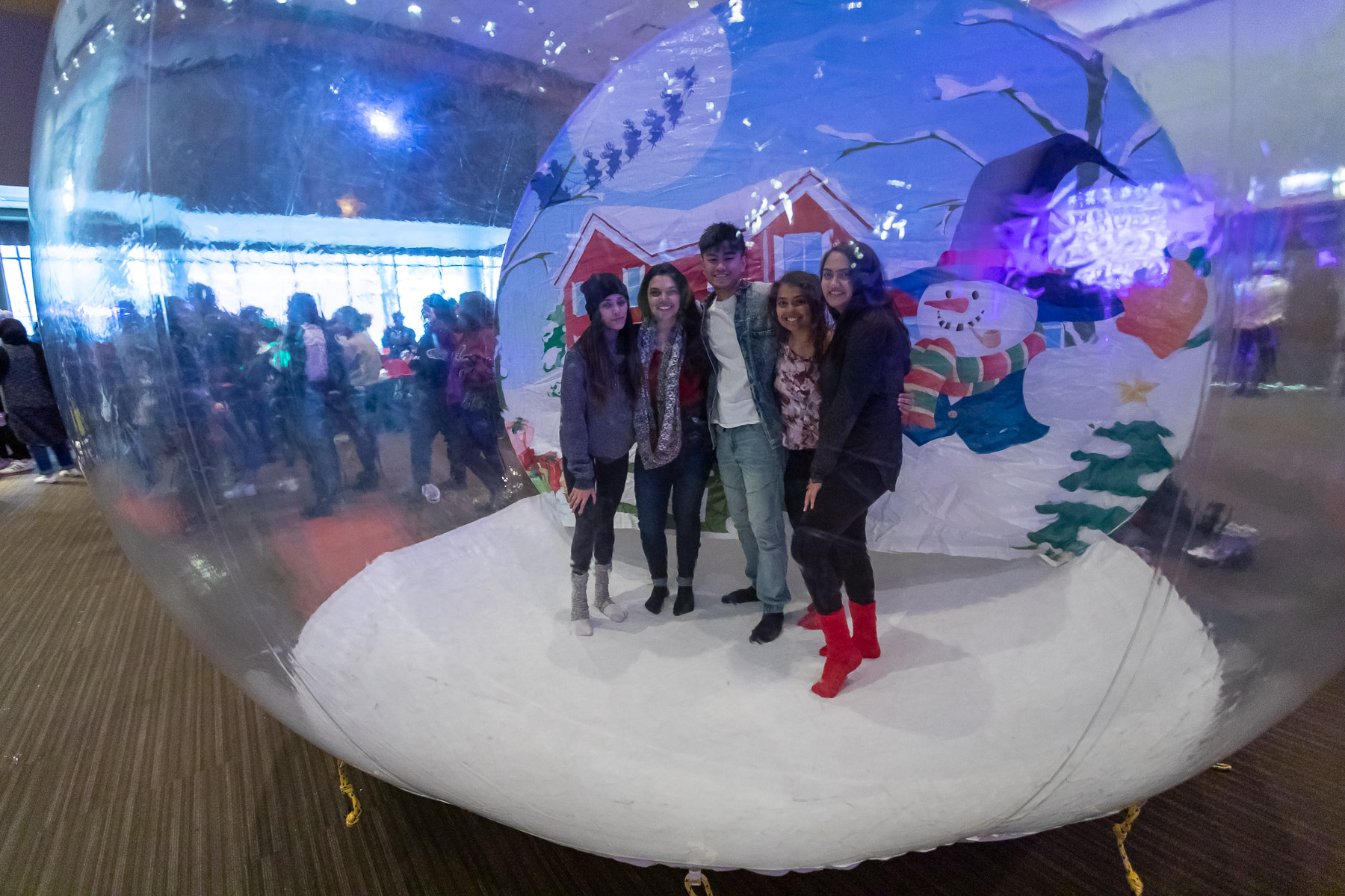 Students take pictures inside an inflatable snow globe before heading out to the Tree Lighting Ceremony. (DePaul University/Jeff Carrion)